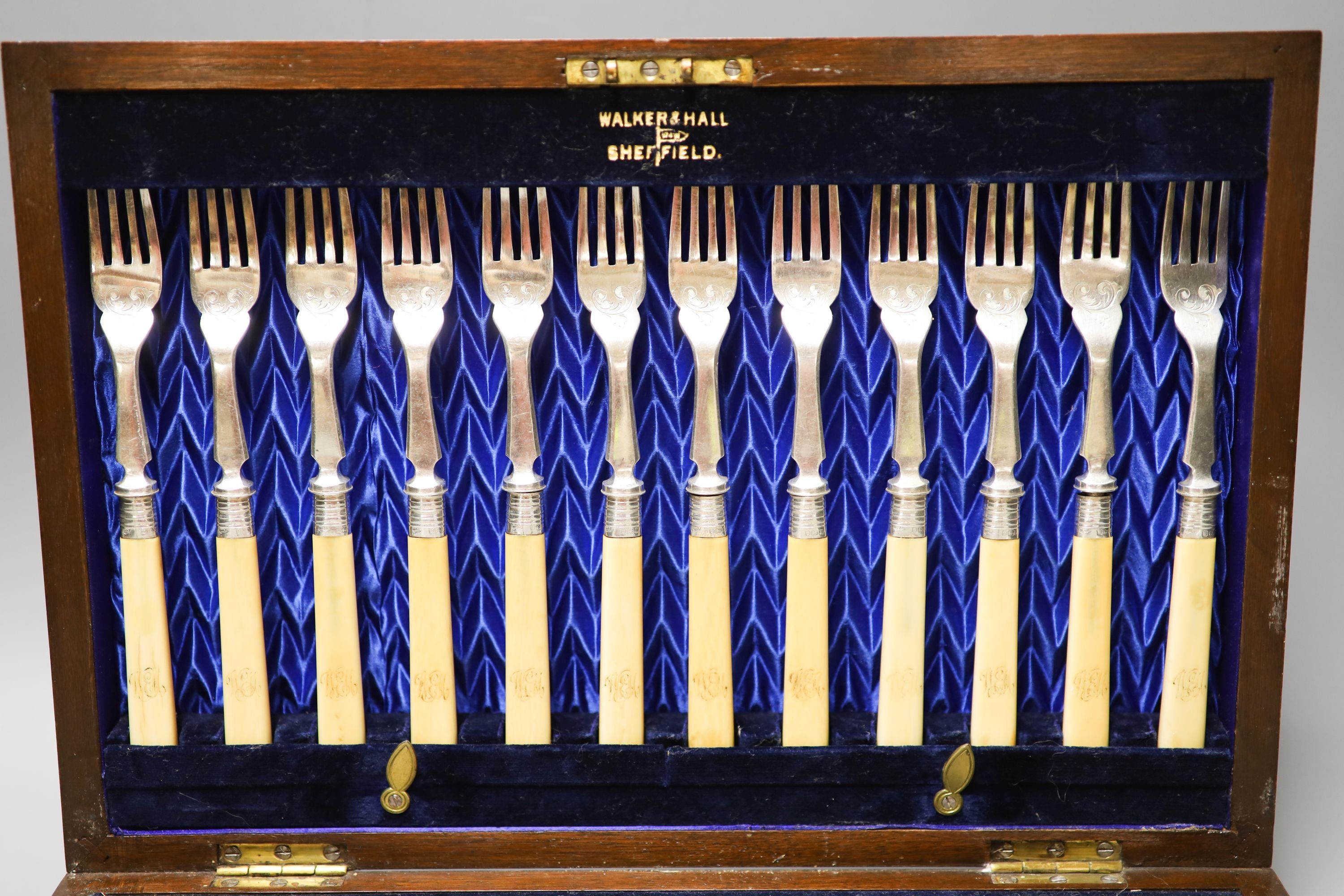 An Edwardian cased set of twelve pairs of ivory handles silver fish eaters, Walker & Hall, Sheffield, 1903.